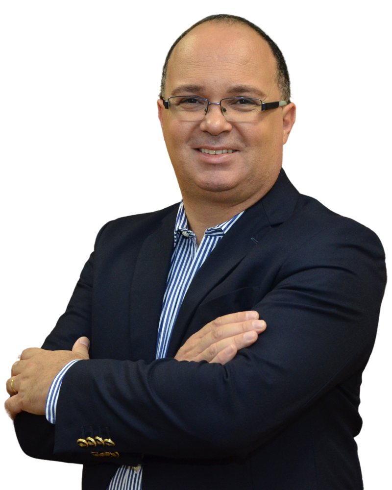 Jorge Araujo sorrindo, de blazer azul-marinho e braços cruzados